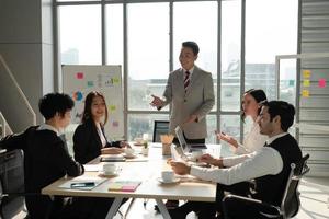 Asiatischer Manager bespricht Projekt mit multiethnischem Team in Besprechung