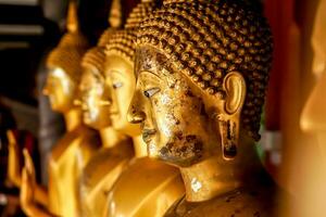 Nahaufnahme und Ernte Altes und goldenes Gesicht der goldenen Buddha-Statue auf verschwommenem goldenem Buddha-Statuenstand starke Linie Hintergrund foto