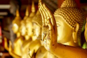 Nahaufnahme und Ernte Hand der goldenen Buddha-Statue mit einem Blattgold auf unscharfer goldener Buddha-Statue stehen starker Linienhintergrund foto