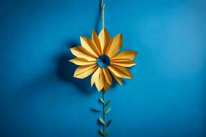 ein Gelb Papier Blume hängend von ein Blau Mauer. KI-generiert foto