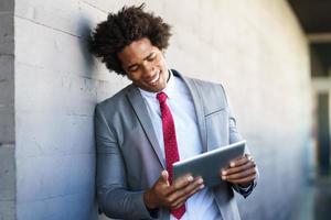 schwarzer Geschäftsmann mit einem digitalen Tablet im städtischen Hintergrund foto