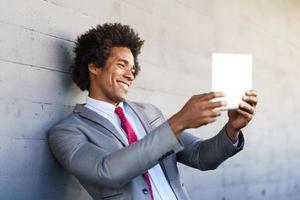 schwarzer Geschäftsmann mit einem digitalen Tablet im städtischen Hintergrund foto