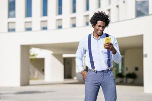 schwarzer Mann mit Afro-Frisur mit einem Smartphone foto