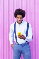 schwarzer Mann mit Afro-Frisur mit Smartphone foto