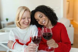 zwei weiblich freunde Ausgaben Zeit zusammen beim heim, Sitzung auf Sofa. Kopieren Raum. heiter Frauen Trinken Wein foto