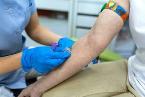 Vorbereitung zum Blut Prüfung mit ziemlich jung Frau durch weiblich Arzt medizinisch Uniform auf das Tabelle im Weiß hell Zimmer. Krankenschwester durchbohrt das Patienten Arm Vene mit Nadel leer Rohr. foto