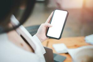 Zelle Telefon Attrappe, Lehrmodell, Simulation Bild leer Weiß Bildschirm, Frau Hand halten SMS mit Handy, Mobiltelefon auf Schreibtisch beim Kaffee Geschäft, Hintergrund leeren Raum zum werben Text. foto