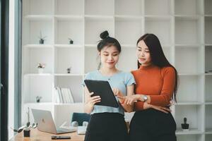 zwei heiter jung multinational Kollegen reden während Stehen im Büro mit Digital Tablette, Geschäft Konzept. foto