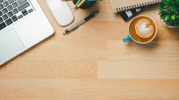 oben Sicht, hölzern Büro Schreibtisch mit Laptop Computer, Tasse von Kaffee, Stift, Maus und Notizbuch, Kopieren Raum, spotten hoch. foto