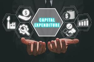 Hauptstadt Ausgaben Konzept, Geschäftsmann Hand halten Hauptstadt Ausgaben Symbol auf virtuell Bildschirm. foto