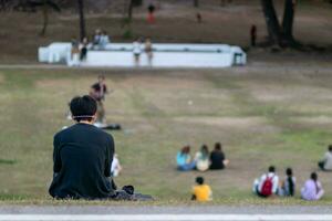 Hintergrund von ein jung Mann Sitzung auf das Gras allein Gefühl einsam und deprimiert weil er hat Depression nach Liebe und Schule Probleme. emotional Stress Konzept verursachen Depression foto