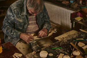 Meisterklasse auf Herstellung hölzern Spielzeuge. Hände von ein Holz Carving Meister mit ein Meißel und ein hölzern Werkstück. foto