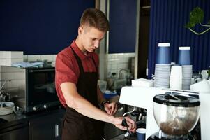 Fachmann Kaffee Brauen. jung trainiert Barista vorbereiten Kaffee auf Fachmann Dampf Kaffee Maschine. foto