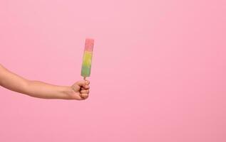 gesund vegan Eis Sahne Eis am Stiel im Hand von ein Baby Mädchen isoliert auf Rosa Mauer Hintergrund mit Kopieren Raum . Sommer- Dessert und heiter Sommer- Stimmung Konzept foto