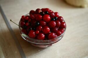 Nahansicht Essen Bild von frisch Süss köstlich fertig für den Verzehr reif Kirsche Beeren im transparent Glas Schüssel auf das Küche Schalter. oben Aussicht foto