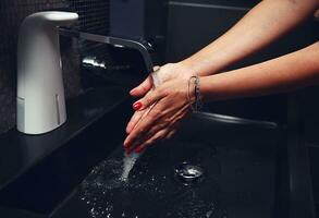 Nahansicht von weiblich gepflegt Hände. ein Frau wäscht ihr Hände gründlich unter Laufen Wasser foto