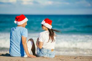 Weihnachtsglückliches Paar in Weihnachtsmützen im Strandurlaub foto