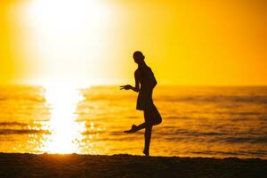 Silhouette des schönen Mädchens, das einen wunderschönen Sonnenuntergang am Strand genießt foto