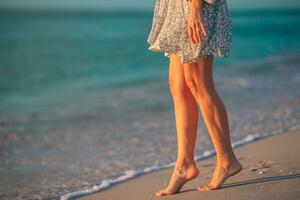 weibliche beine am strand nahaufnahme. Frau im Kleid am Strand spazieren foto