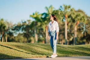 glücklich jung Frau Gehen draussen im das Park foto