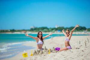 Mutter und Tochter genießen Zeit auf das Strand. Familie Herstellung Sand Schloss zusammen auf das Strand foto