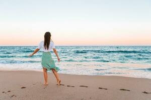 junge glückliche Frau am Strand genießt ihren Sommerurlaub. Mädchen ist glücklich und ruhig in ihrem Aufenthalt am Strand foto