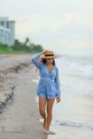 schön Teenager Mädchen auf tropisch Strand beim Sonnenuntergang. schön wenig Mädchen im Kleid beim Strand haben Spaß. glücklich Mädchen genießen Sommer- Ferien Hintergrund das Blau Himmel und Türkis Wasser im das Meer foto