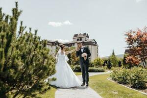 glücklich Mann und Gattin. Hochzeit Tag. schön Natur. gehen während das Foto Sitzung. Sie Lächeln beim jeder andere. halten Hände.