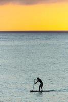 Silhouette des Mannes mit seinem Stand Up Paddle am Strand von Ipanema, in Rio de Janeiro, Brasilien