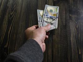 Hand mit Geld auf einem hölzernen Hintergrund