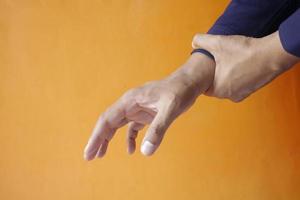 Mann leidet Schmerzen in der Hand vor orangem Hintergrund foto