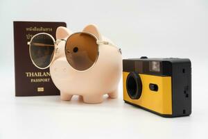 Speichern zum Ferien und Budget Konzept. Film Kamera, Reisepass, Schweinchen Bank tragen Sonnenbrille zum Ferien Reise. vorbereiten zum Urlaub. foto