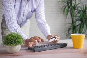 Mannhände, die Kreditkarte halten und mit Laptop online einkaufen