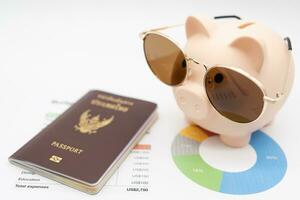 Budget Verwaltung zum Ferien Konzept. Reisepass, Schweinchen Bank tragen Sonnenbrille zum Ferien Ausflug und Budget Graph. vorbereiten zum Urlaub. foto