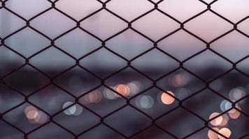 Maschendrahtzaun mit hellem Bokeh bei Sonnenuntergang Hintergrund foto