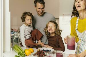 glücklich Familie Herstellung ein Smoothie im Küche foto