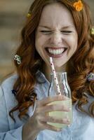 Porträt von Lachen rothaarig Frau mit Blüten im Haar Trinken Limonade foto