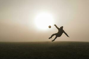 jung Mann spielen Fußball auf Wiese im das Abend foto