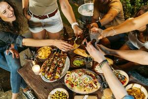 glücklich freunde Toasten mit Bier Flaschen während ein draussen Abendessen foto