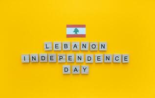November 22, libanesisch Unabhängigkeit Tag, das Flagge von Libanon, ein minimalistisch Banner mit das Inschrift im hölzern Briefe auf ein Orange Hintergrund foto
