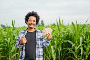 lächelnd asiatisch Farmer und Geld. Grün Bauernhof foto