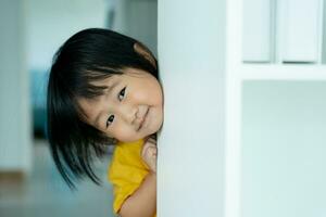 wenig asiatisch Kinder Kind spielen ausblenden und suchen Stehen Nächster Mauer Haus, bezaubernd Kind haben Spaß im das heim. glücklich Familie haben Spaß mit Kinder, Aktivität, Lernen, Aktivität, Spiel, Meditation foto