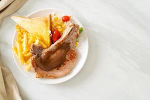 Schweinekotelettsteak mit Pommes und Minisalat auf weißem Teller foto