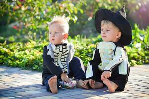 wenig Junge Sitzung tragen ein Skelett Kostüm und ein schwarz Hut. foto