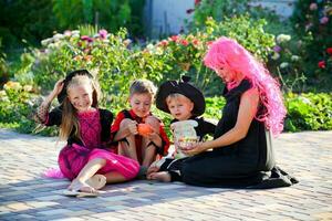 Kinder und ein Frau sind Sitzung auf das Straße im Halloween Kostüme. foto