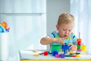 wenig Junge 2 Jahre alt ist gespielt mit ein Farben Spielzeuge. lehrreich Logik Spielzeuge zum Kinder. montessori Spiele zum Kind Entwicklung. foto