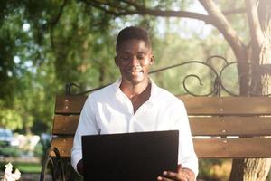 afroamerikanischer Geschäftsmann, der an einem Laptop auf einer Parkbank arbeitet, foto