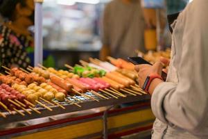 Frau mit Smartphone für Geld für Streetfood foto