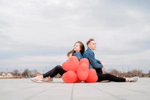 Paar sitzt mit einem Haufen roter Luftballons und verbringt Zeit miteinander foto