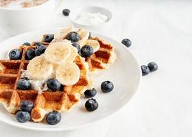 frisch gebackene Waffeln mit Blaubeeren, Banane und Joghurt foto